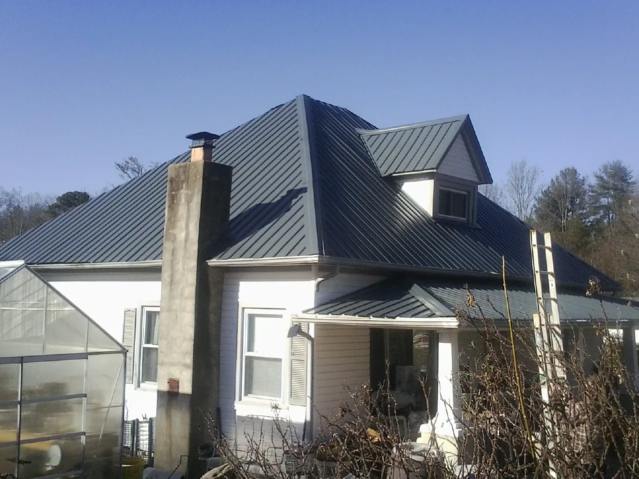 Dark blue standing seam metal roof on a white farmhouse with dormer — Slate & Tile Roof Repair by Roofing Brothers in Harpster