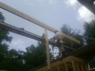 Carpenter setting a ridge beam over a new addition frame — Ice Dam Removal by Roofing Brothers in Harpster