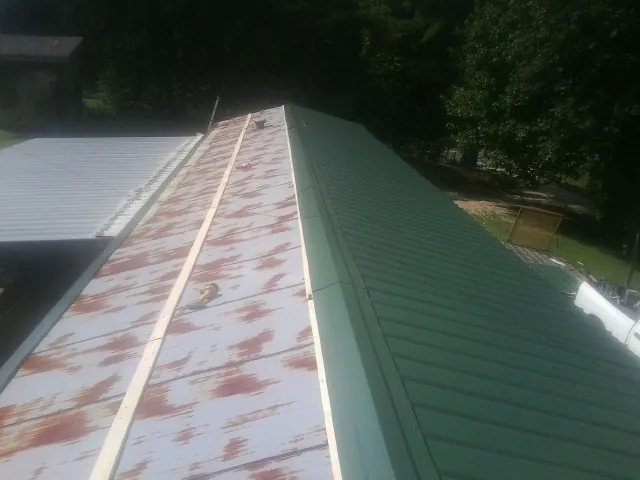 Old rusted panels beside newly installed green metal roofing — Wind Damage Roof Repair by Roofing Brothers in Harpster