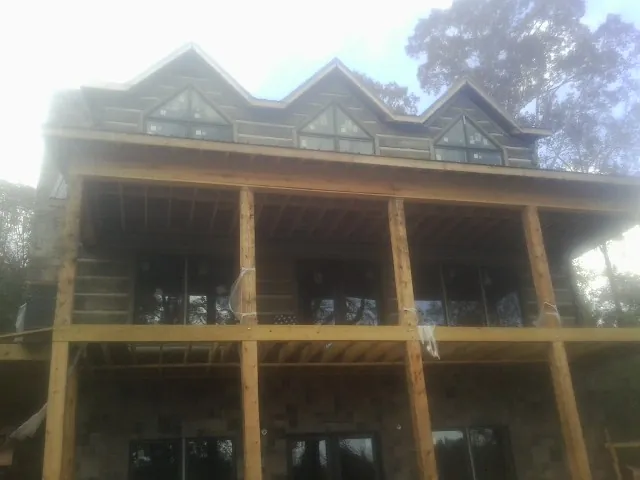 Dormers and porch framing on a large log home under construction — Roof Coating work by our crew in Harpster