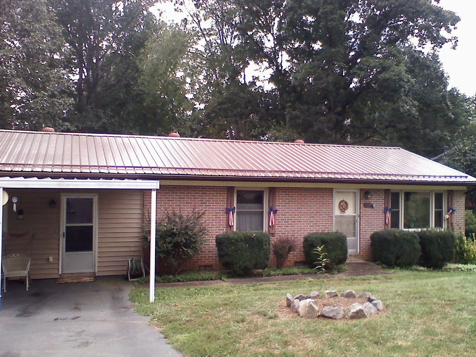Bronze metal roof and carport on a brick ranch home — Roof Repair work by our crew in Harpster