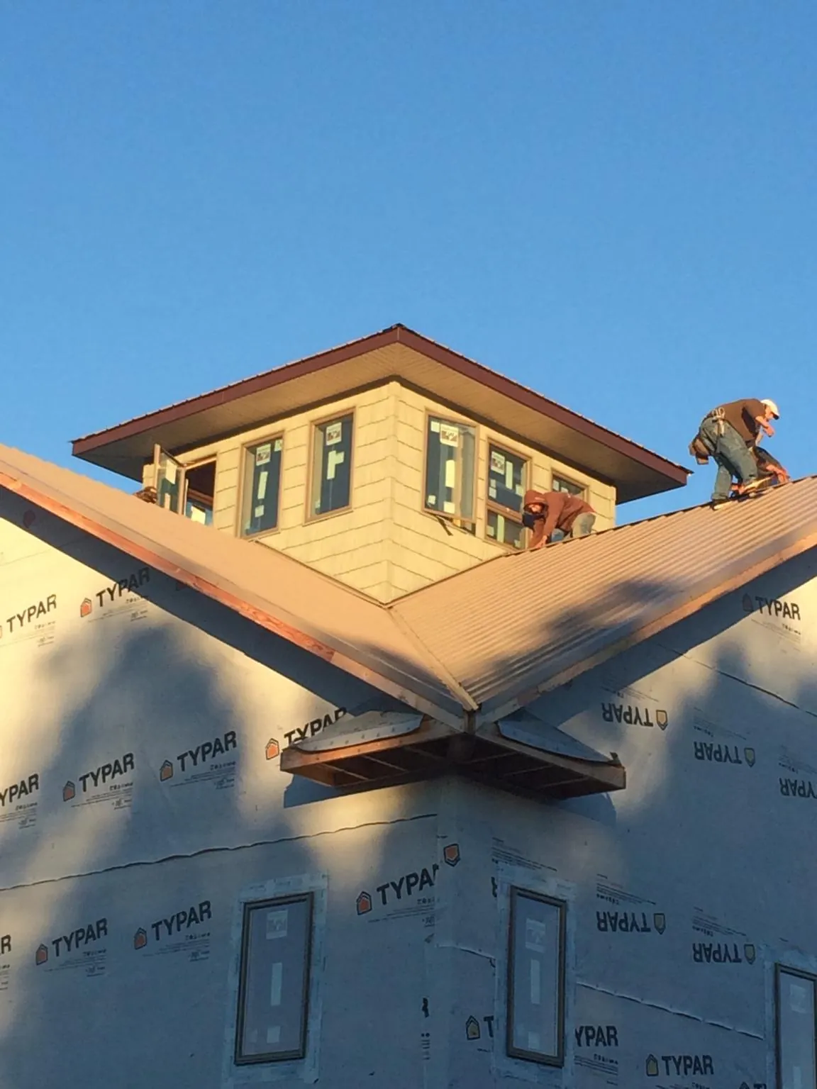 Roofers working around a rooftop cupola on a new metal roof at sunset — Roof Waterproofing in Harpster by Roofing Brothers